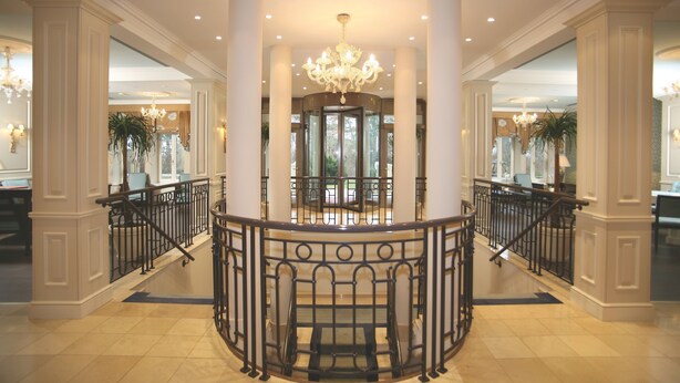 Um hall imponente com uma rotunda central, tetos altos e um lustre.