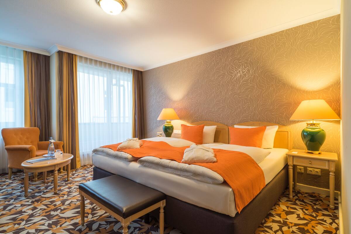 Ein Hotelzimmer mit einem Bett, einem Sessel, einem kleinen Tisch und einer Lampe.