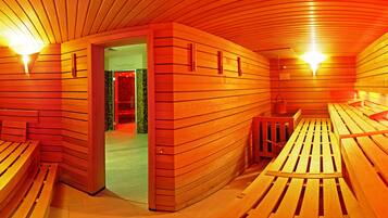 A sauna with wooden benches and walls, a door leading to a room with a red and green mosaic wall, and two wall-mounted lights.