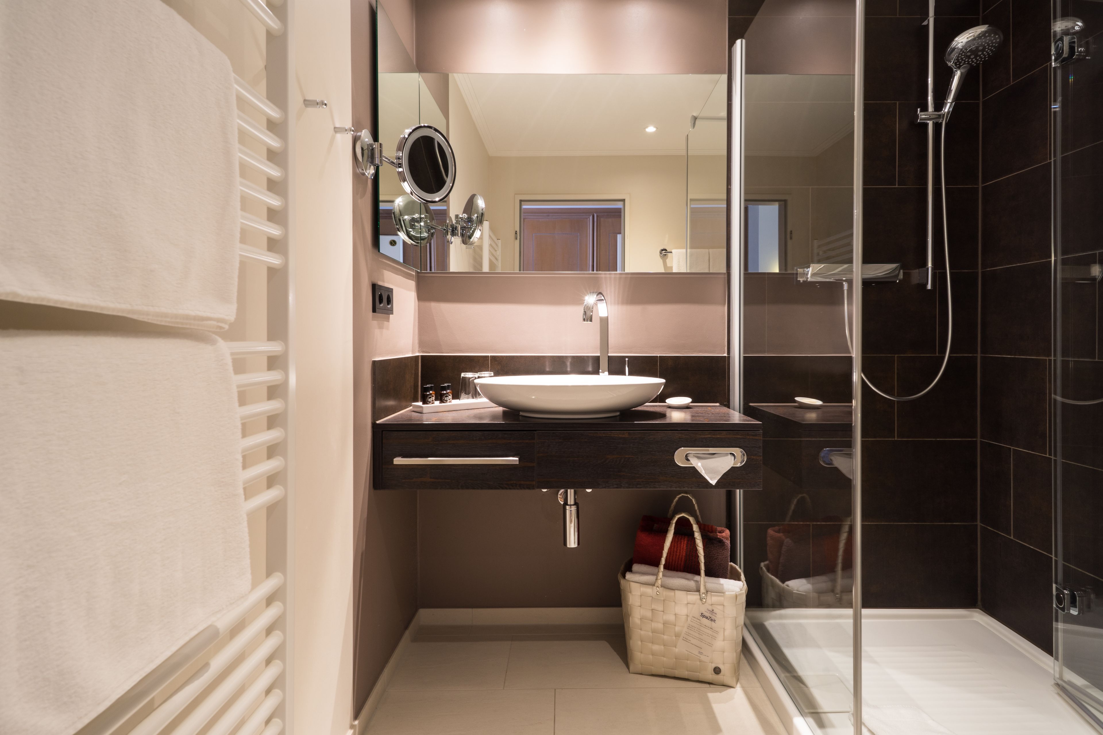 A modern bathroom with a large mirror, a sink, and a shower.