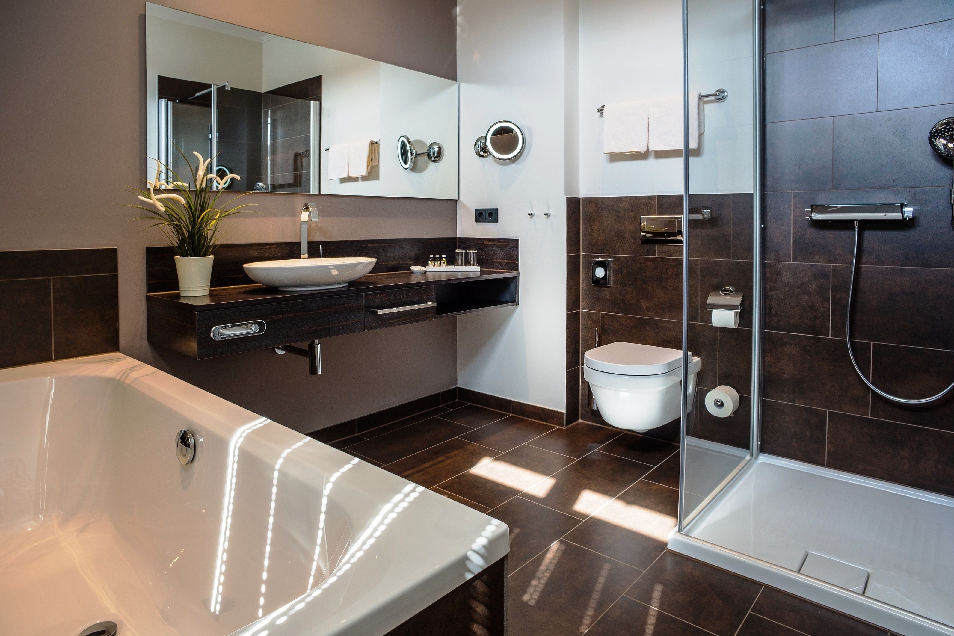 Un baño moderno con bañera, lavamanos, inodoro y ducha con mampara de vidrio.