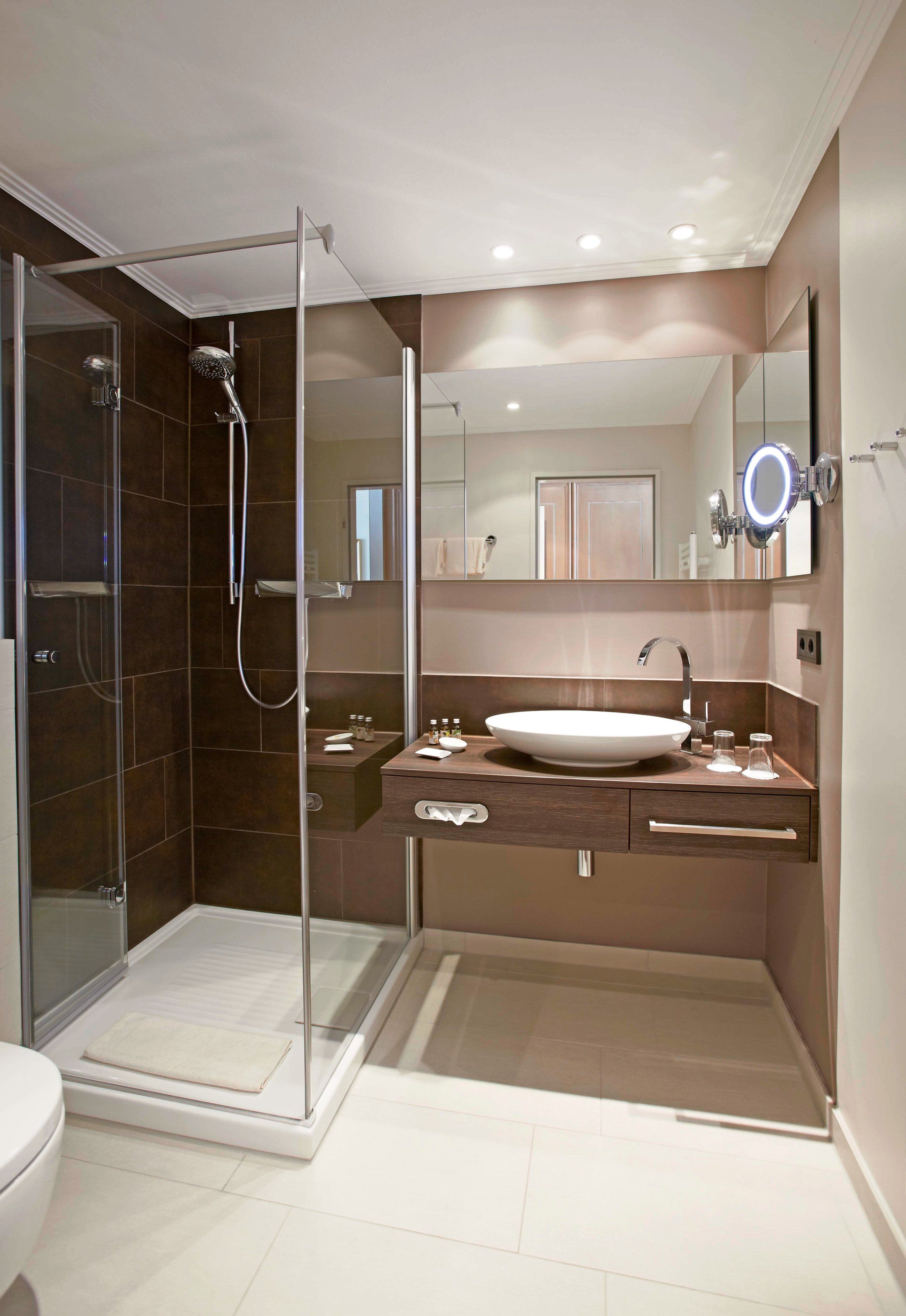 Un baño moderno con ducha de vidrio, un lavabo blanco y un tocador con espejo.