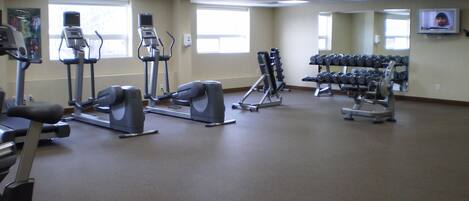 A gym with treadmills, elliptical machines, and dumbbells.