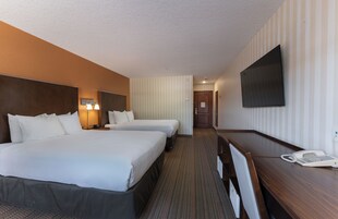 A hotel room with two beds, a desk with a telephone, and a TV mounted on the wall.
