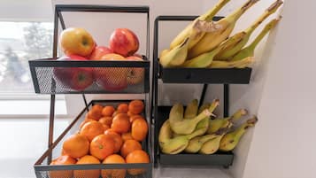 Two metal mesh fruit baskets on a countertop, one containing apples and oranges, the other bananas.