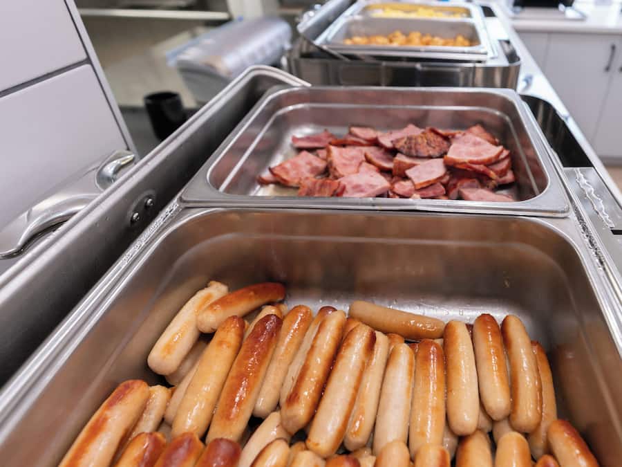 Un bufé con salchichas y jamón en rodajas.