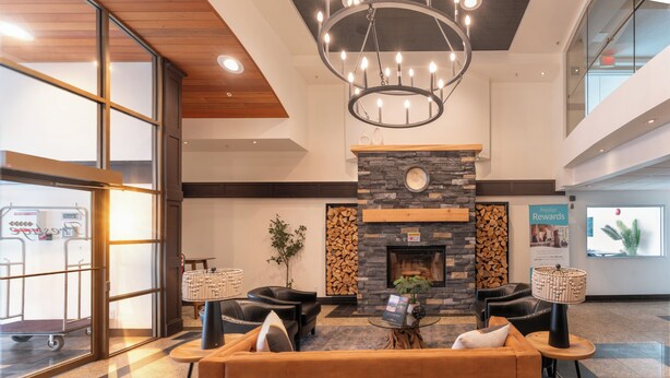 A lobby with a fireplace, seating area, and a sign for 'Rewards.' - Prestige Prince George Lodge (Prince George)
