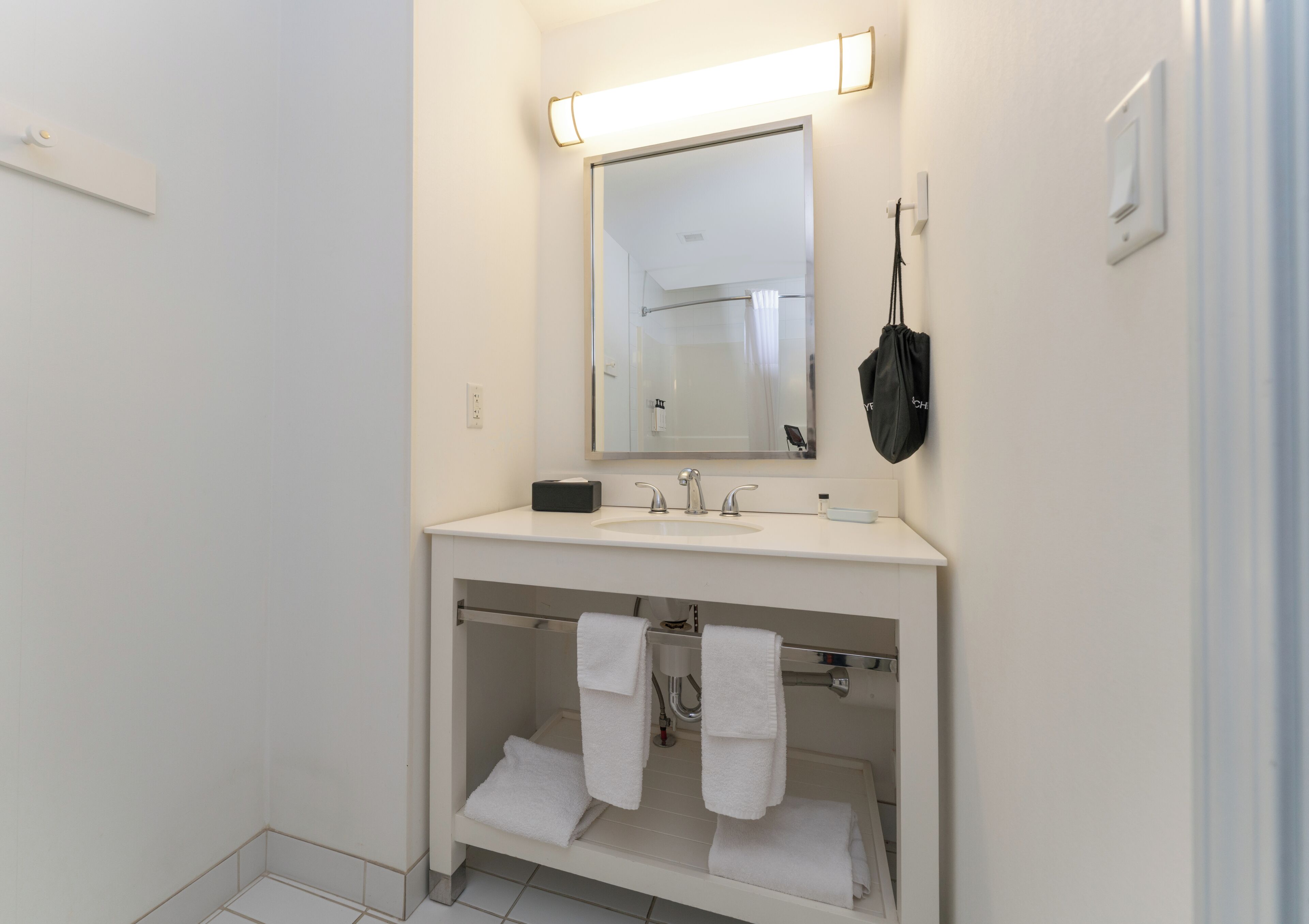 A bathroom with a white sink, mirror, and towel rack.