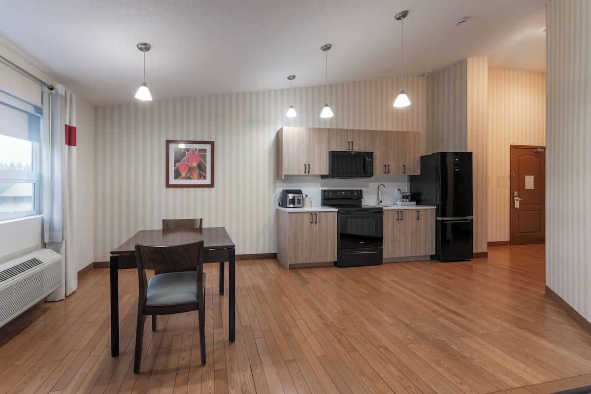 Eine moderne Küche mit Holzschränken, einer Mikrowelle, einem Kühlschrank und einem Essbereich mit Tisch und Stühlen.
