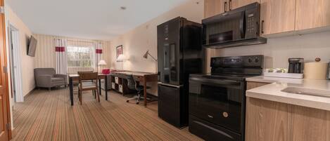 Cocina compacta con refrigerador, microondas, horno y pileta. Hay un comedor con mesa y sillas.