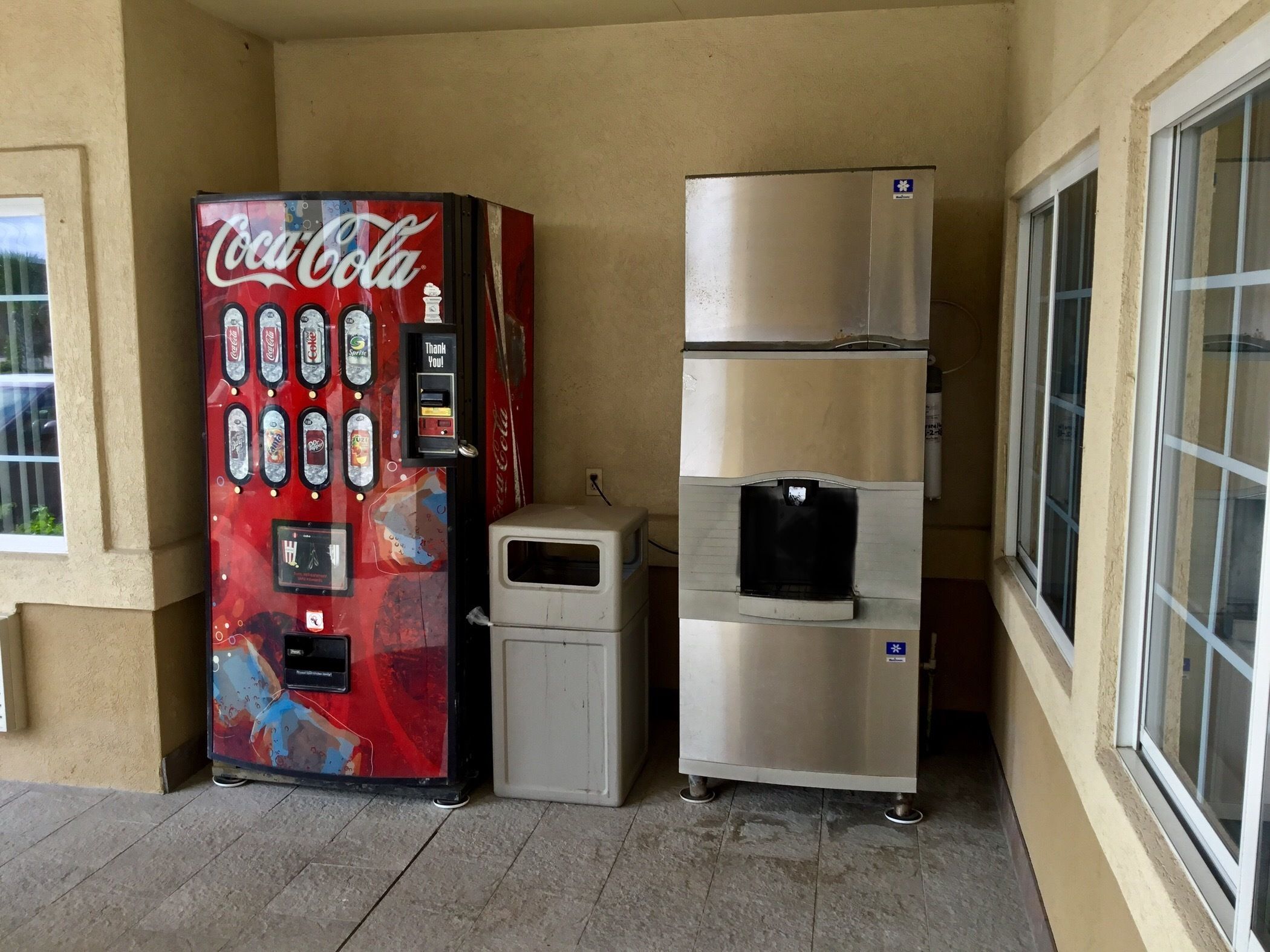 Un distributeur automatique de Coca-Cola et un réfrigérateur en acier inoxydable sur un balcon.