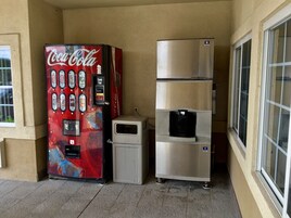 Una máquina expendedora de Coca-Cola y un refrigerador de acero inoxidable en un balcón.