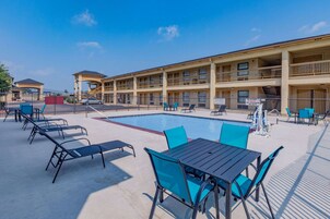 Un hotel con piscina, zona de estar al aire libre y un edificio de varios pisos.