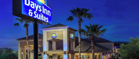A Days Inn & Suites hotel with a prominent sign, palm trees, and well-lit exterior.