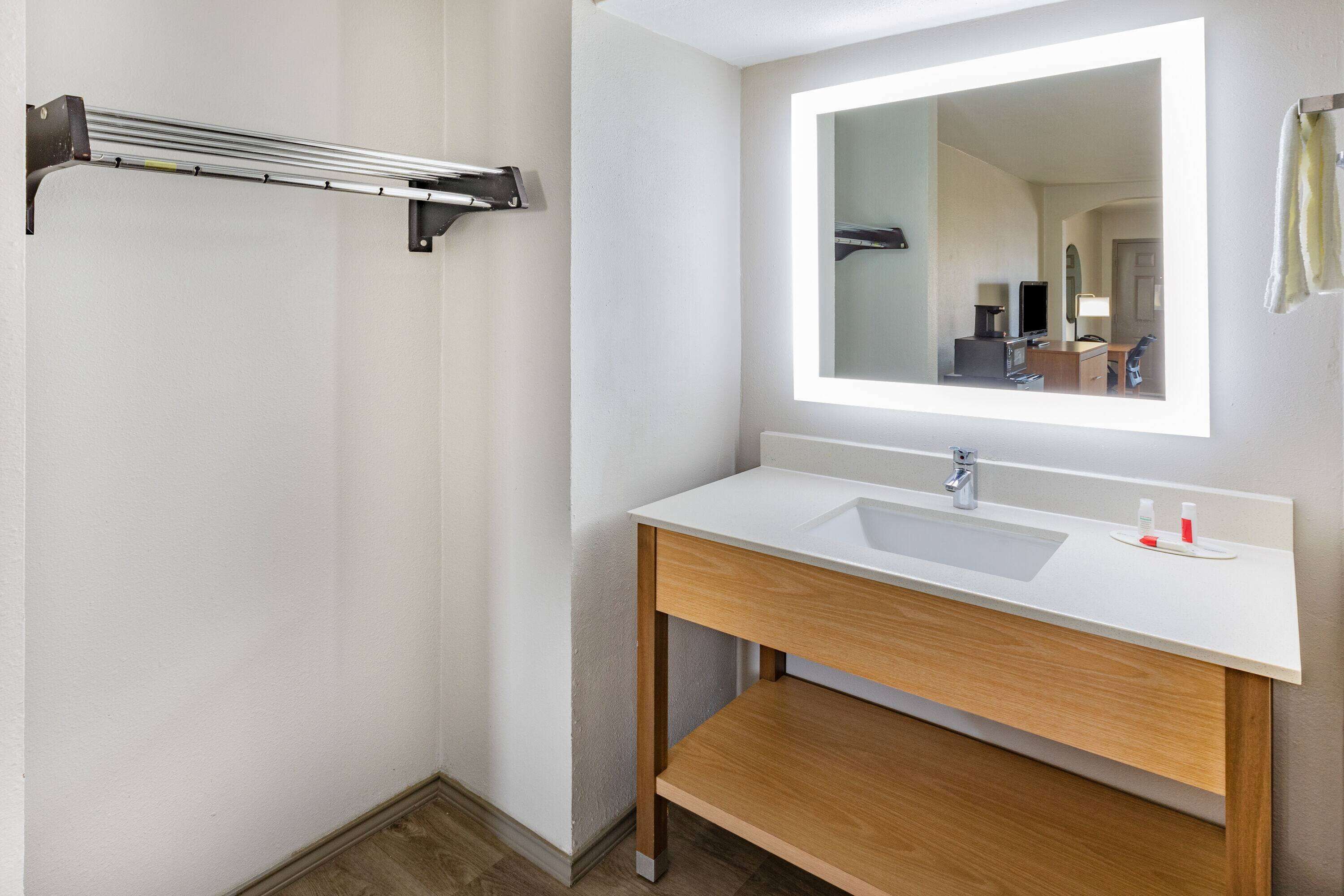 A modern bathroom with a white sink, wooden vanity, and a large mirror.