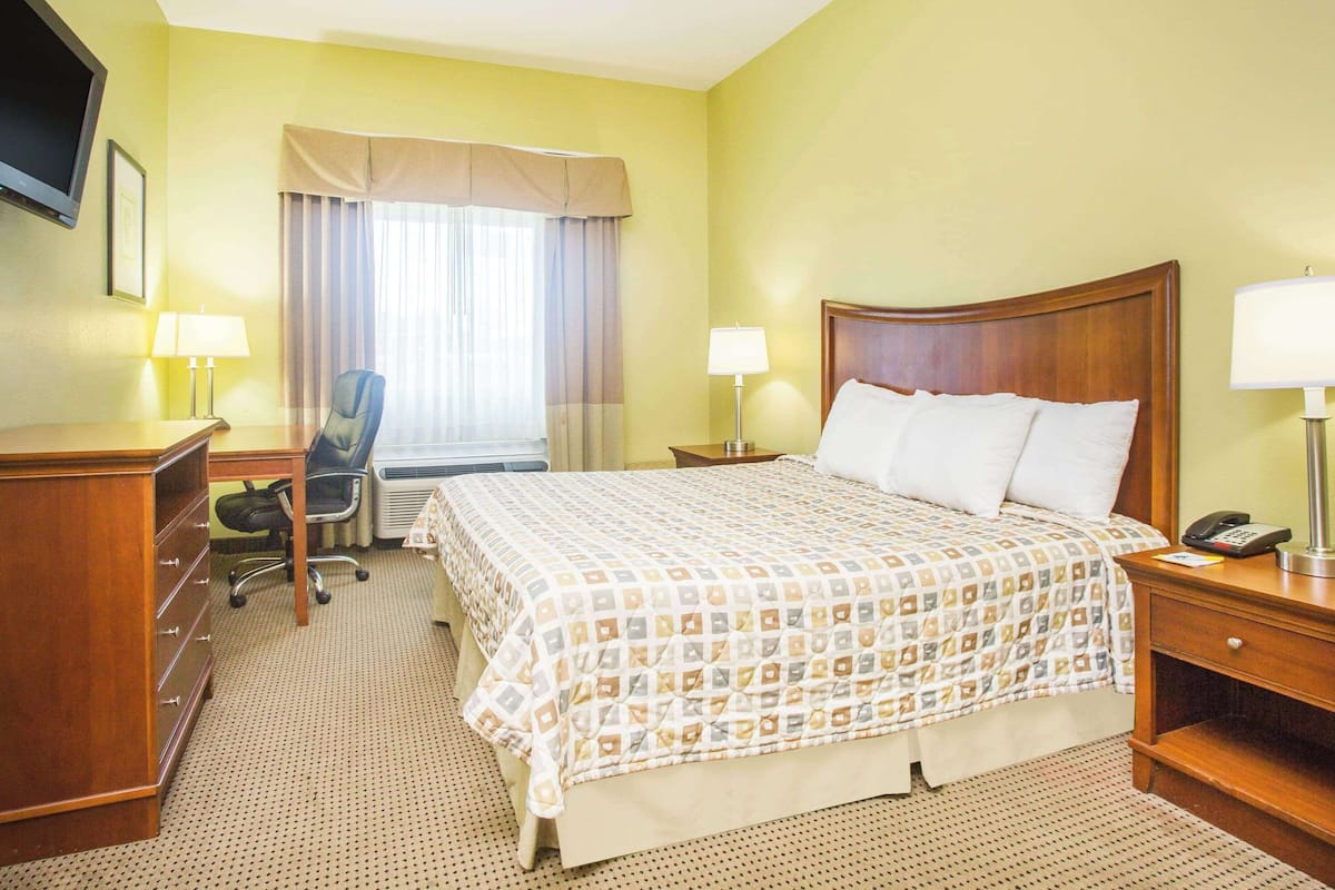 A hotel room with a bed, desk, chair, and two bedside lamps.