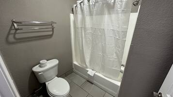 Un baño con inodoro, ducha con cortina y toallero.