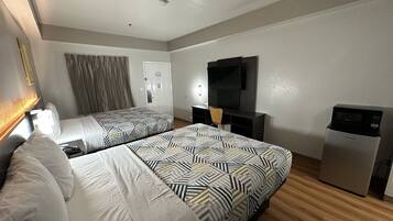 Una habitación de hotel con dos camas, un escritorio, un televisor y un minibar.