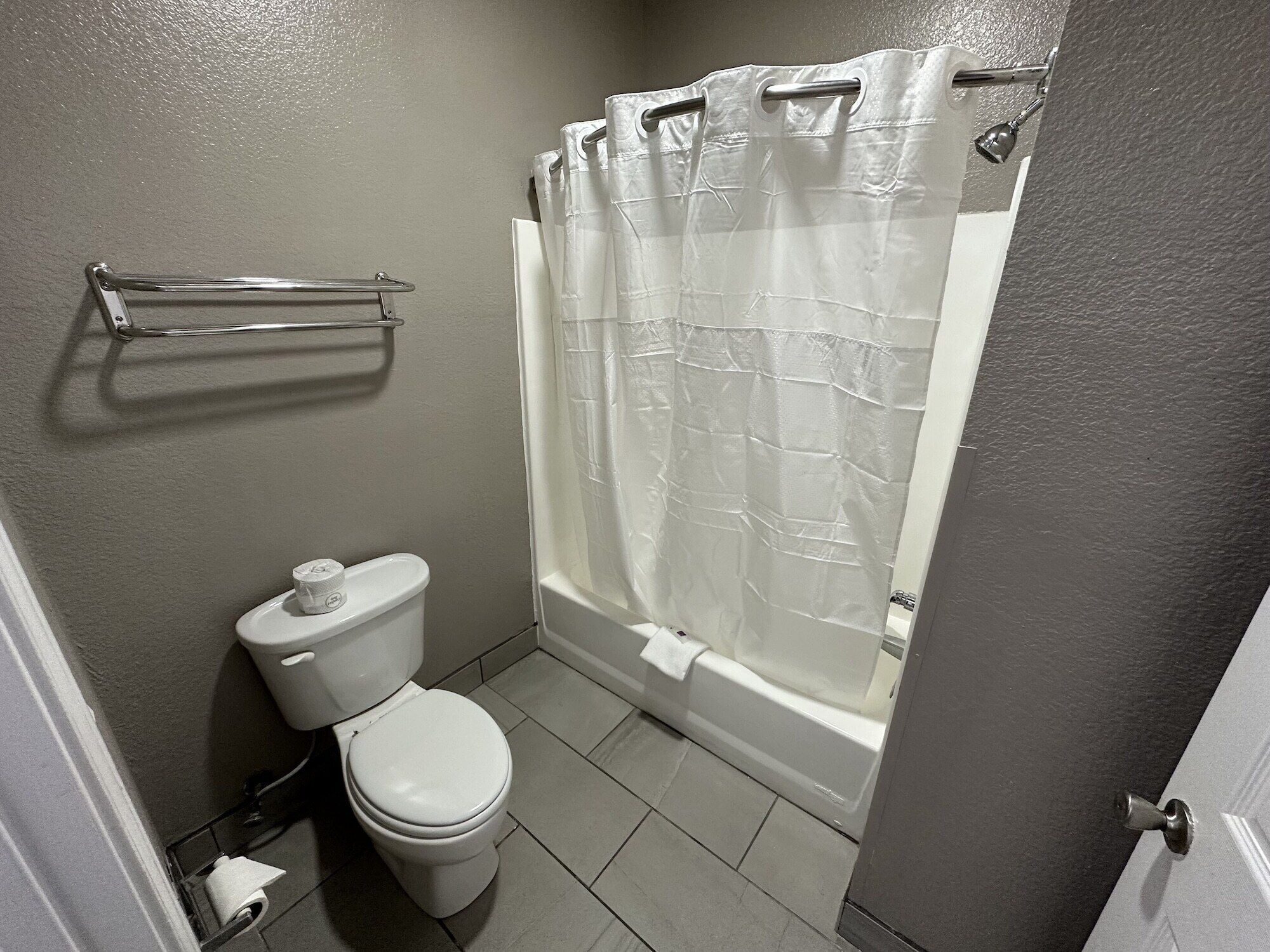 A bathroom with a toilet, a shower curtain, and a towel rack.