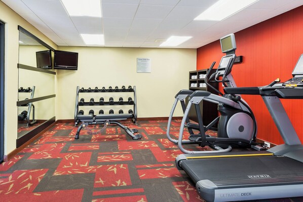 A fitness center with treadmills, elliptical machines, and a weight rack.