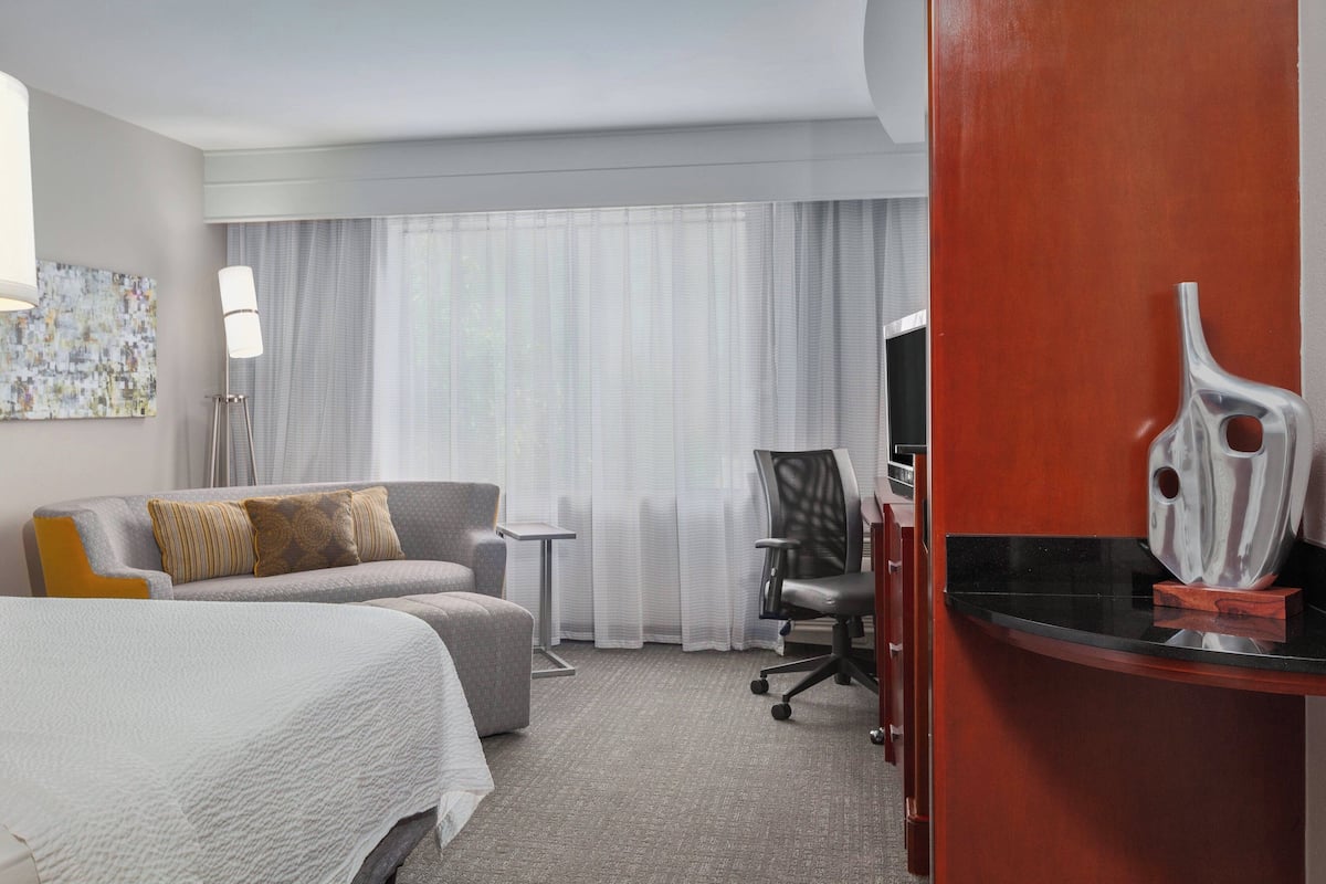 Une chambre d’hôtel avec un lit, un canapé, un bureau et une chaise.