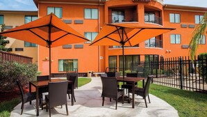 A Courtyard Marriott hotel with outdoor seating and a fenced patio area. - Courtyard by Marriott Corpus Christi (Corpus Christi)