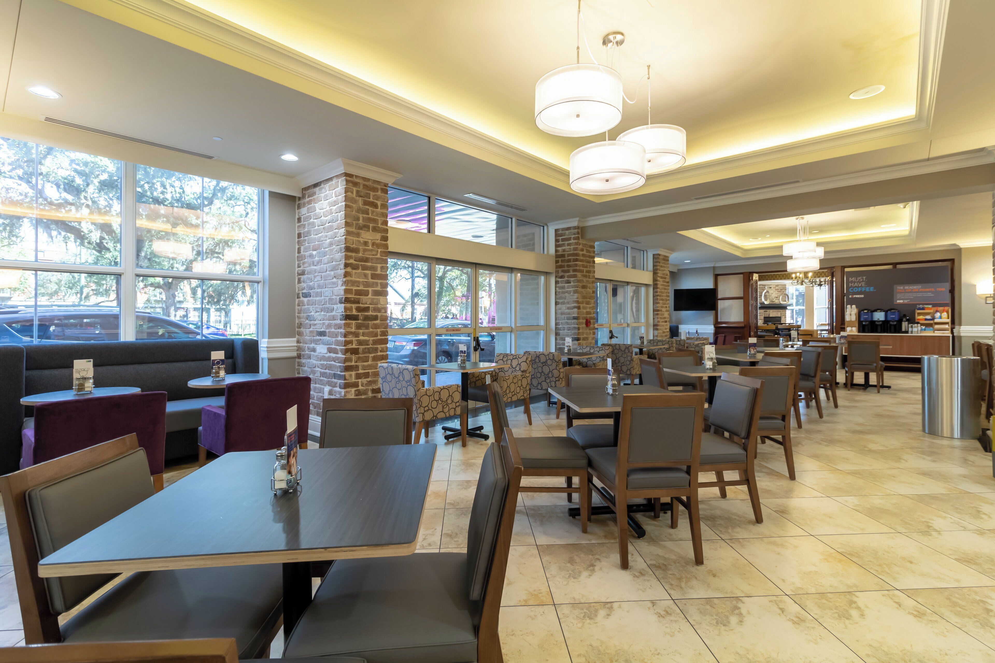 A restaurant with high ceilings, large windows, and a mix of seating options including booths and tables.