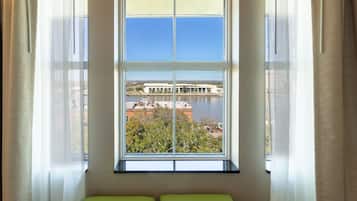 A room with a large window offering a view of a body of water and buildings across the water.
