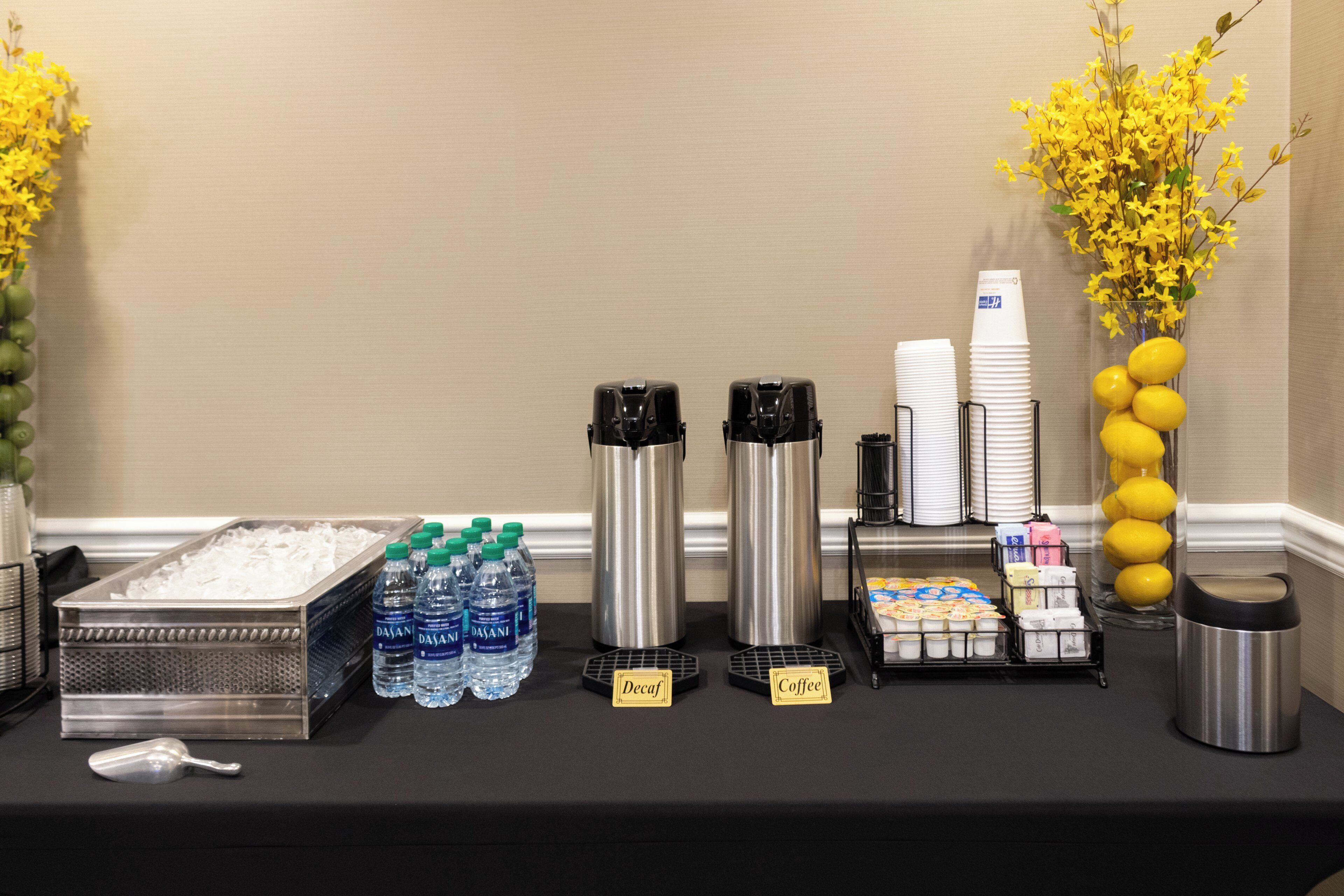 A buffet table with water bottles, coffee, and decaf coffee.