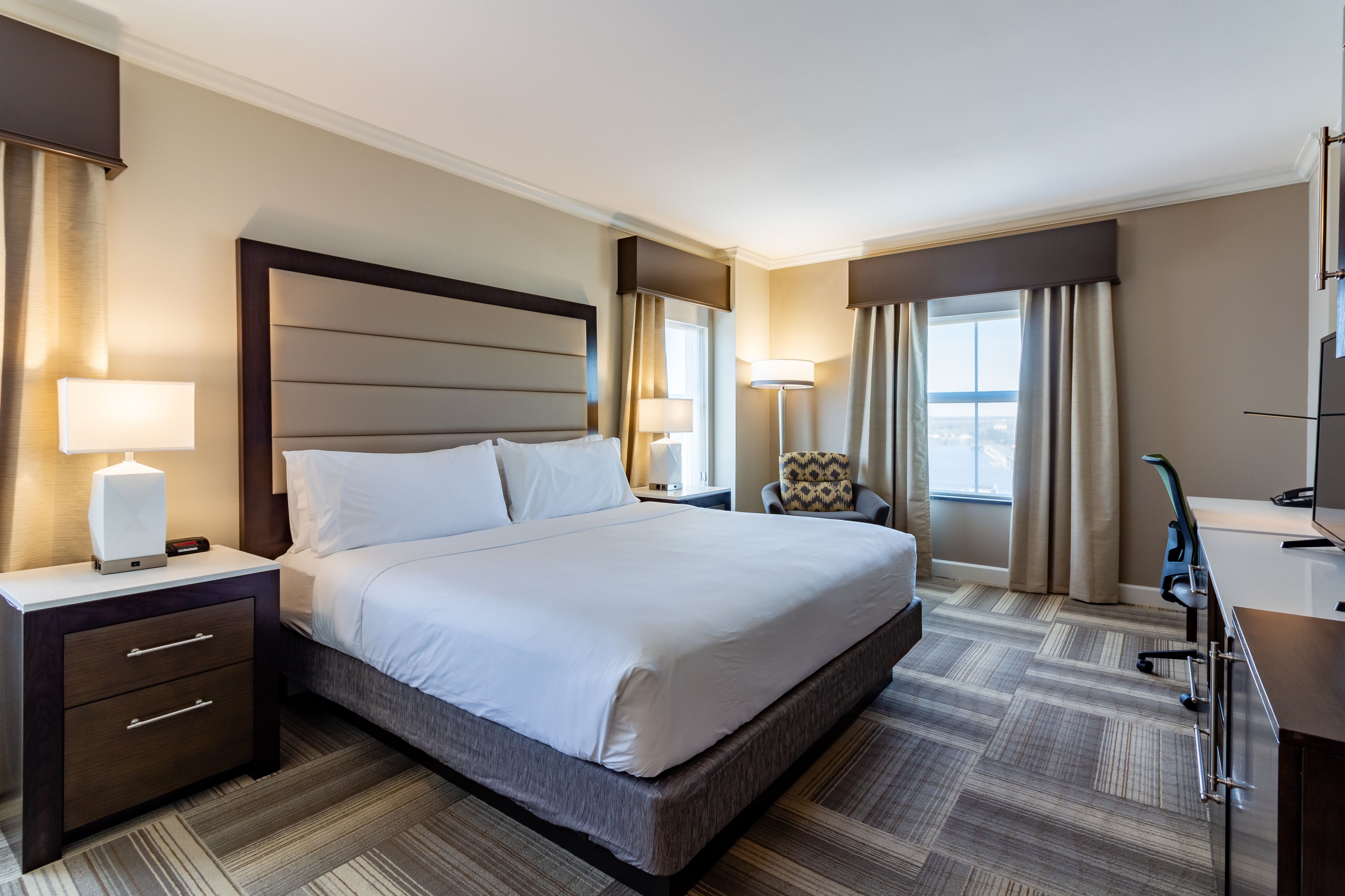 A hotel room with a large bed, bedside tables, a desk, and a chair.
