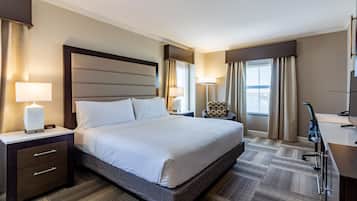 A hotel room with a large bed, bedside tables, a desk, and a chair.