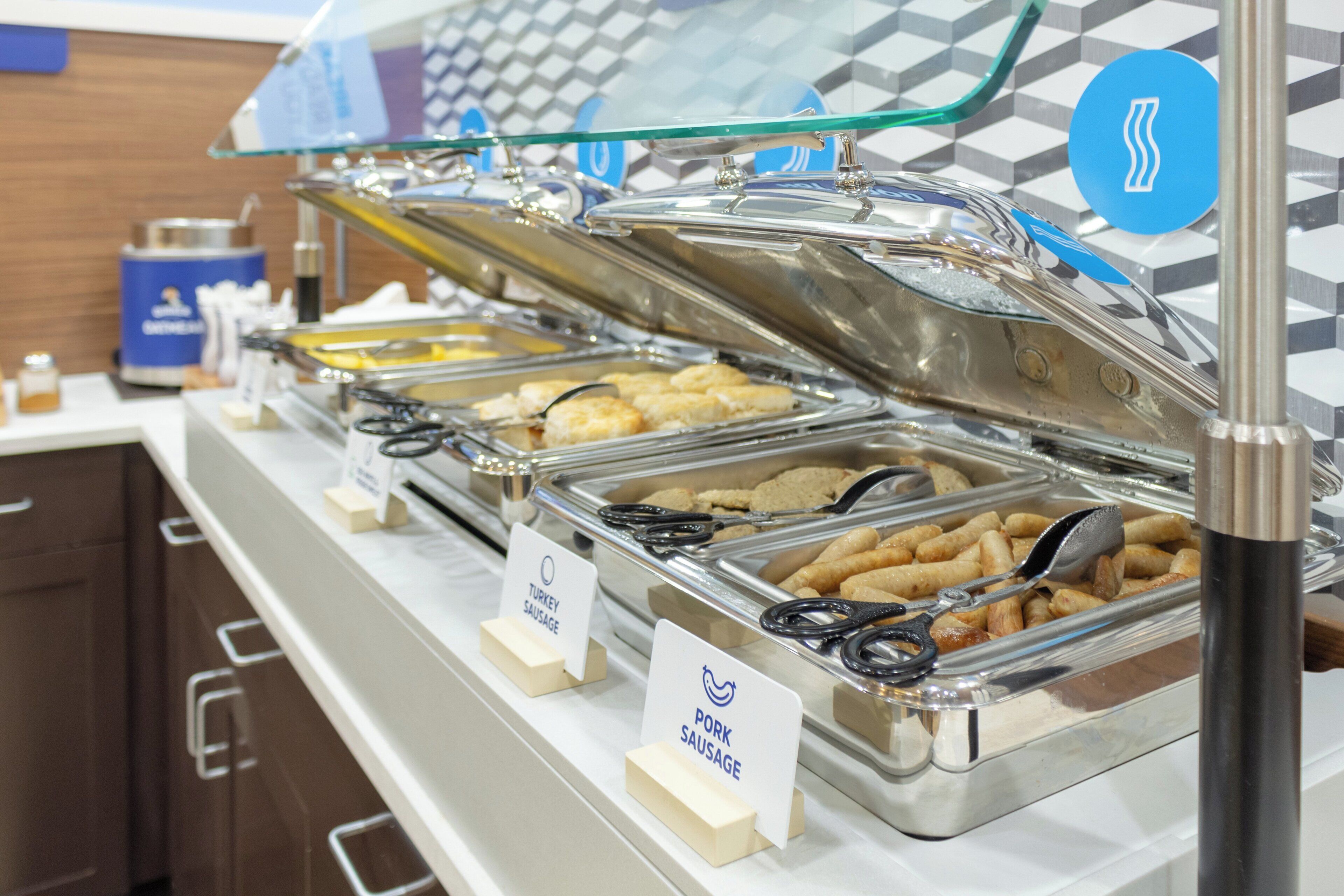 A buffet with labeled trays of turkey, sausage, and other meats.