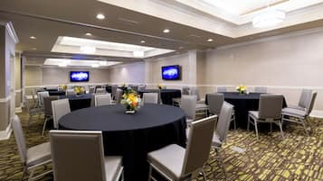A conference room with round tables, chairs, and floral centerpieces.