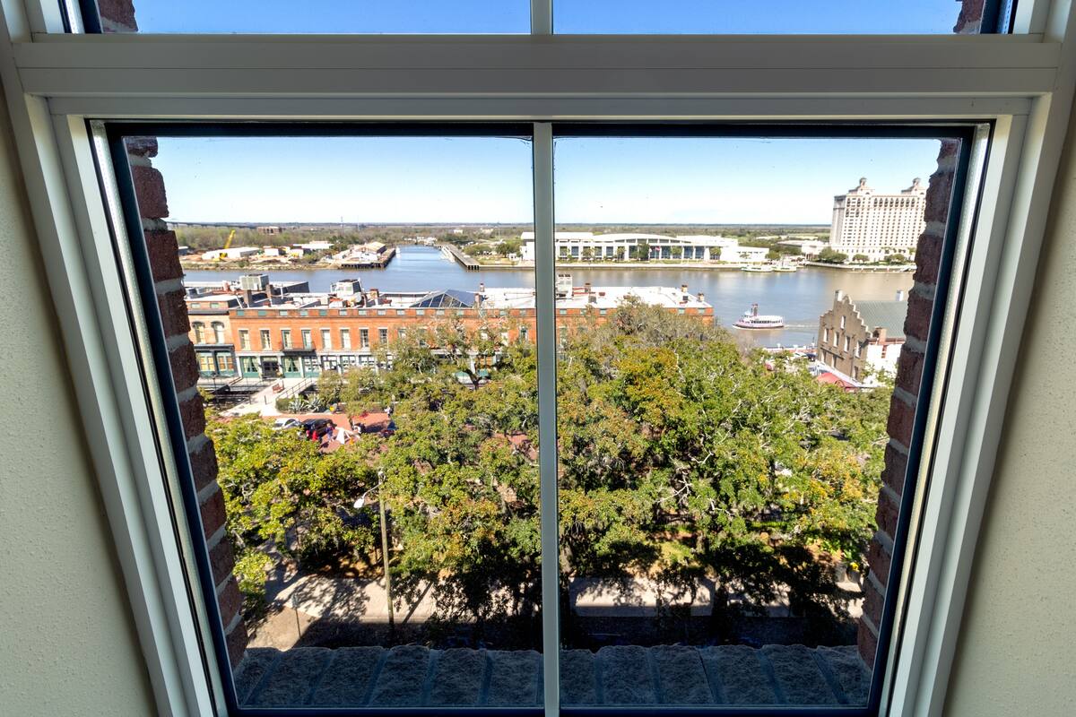 A view from a window overlooking a river with buildings and trees.