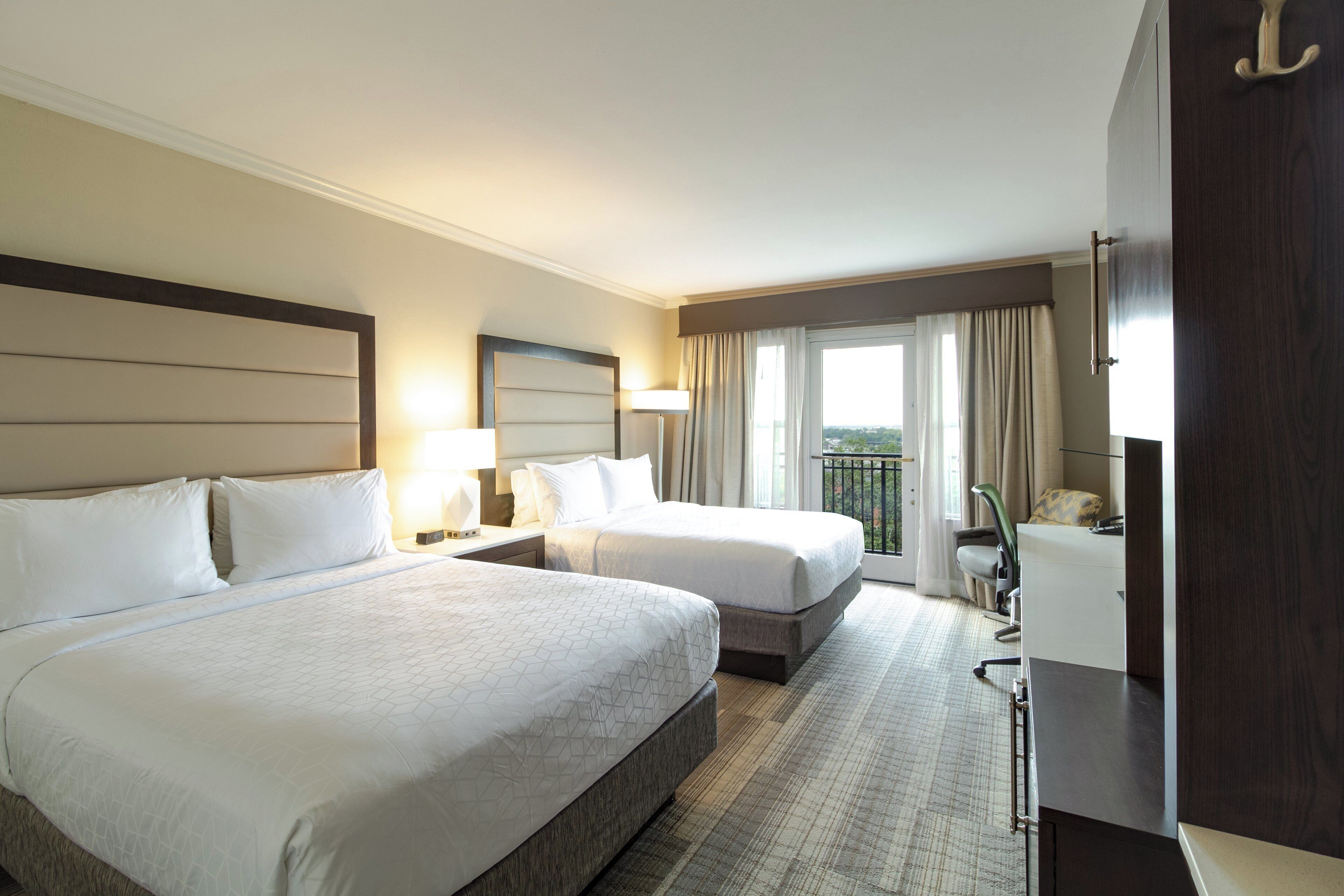 Une chambre d’hôtel avec deux lits, un bureau, une chaise et un balcon avec vue.