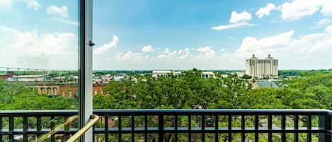 A balcony with a view of a cityscape, including buildings and trees.