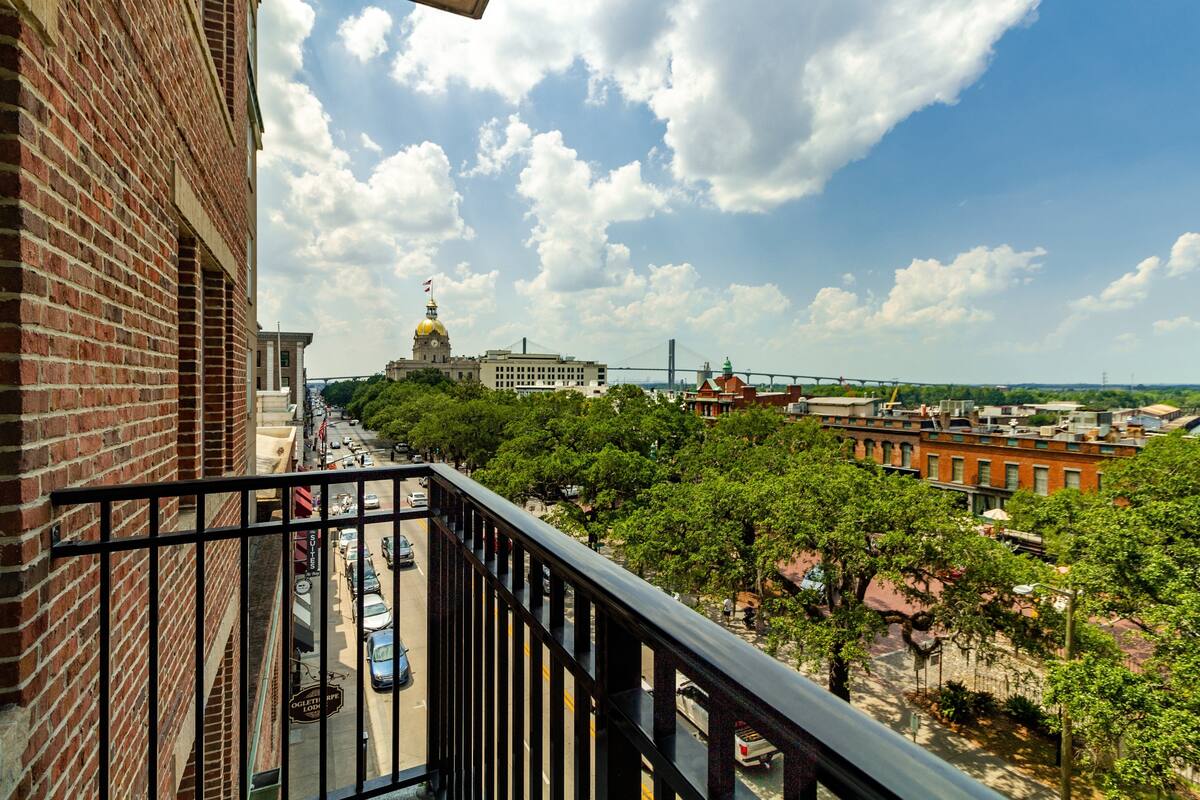 A balcony with a view of a cityscape, including buildings and a bridge.