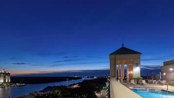 A pool area with a gazebo overlooking a body of water and a cityscape.