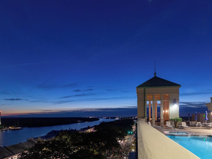 A pool area with a gazebo overlooking a body of water and a cityscape.