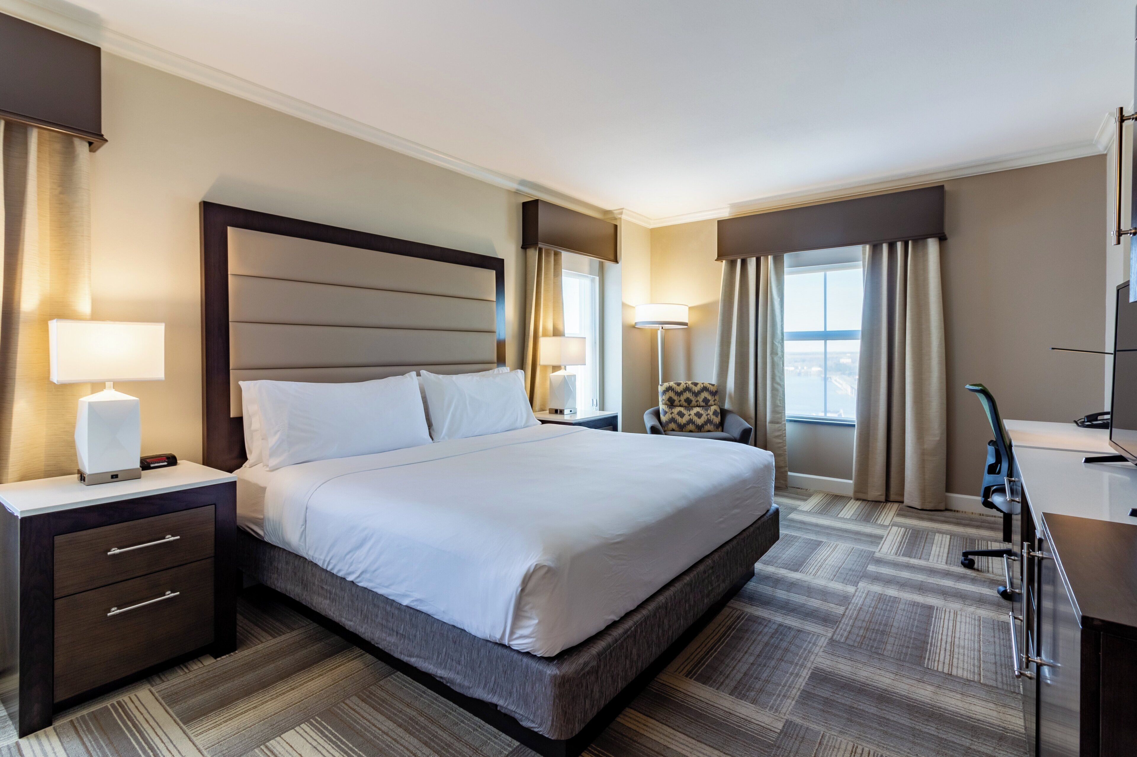 A hotel room with a large bed, bedside tables, a desk, and a chair.