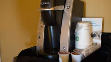 A Keurig coffee maker with a cup of coffee and a disposable cup on a table.