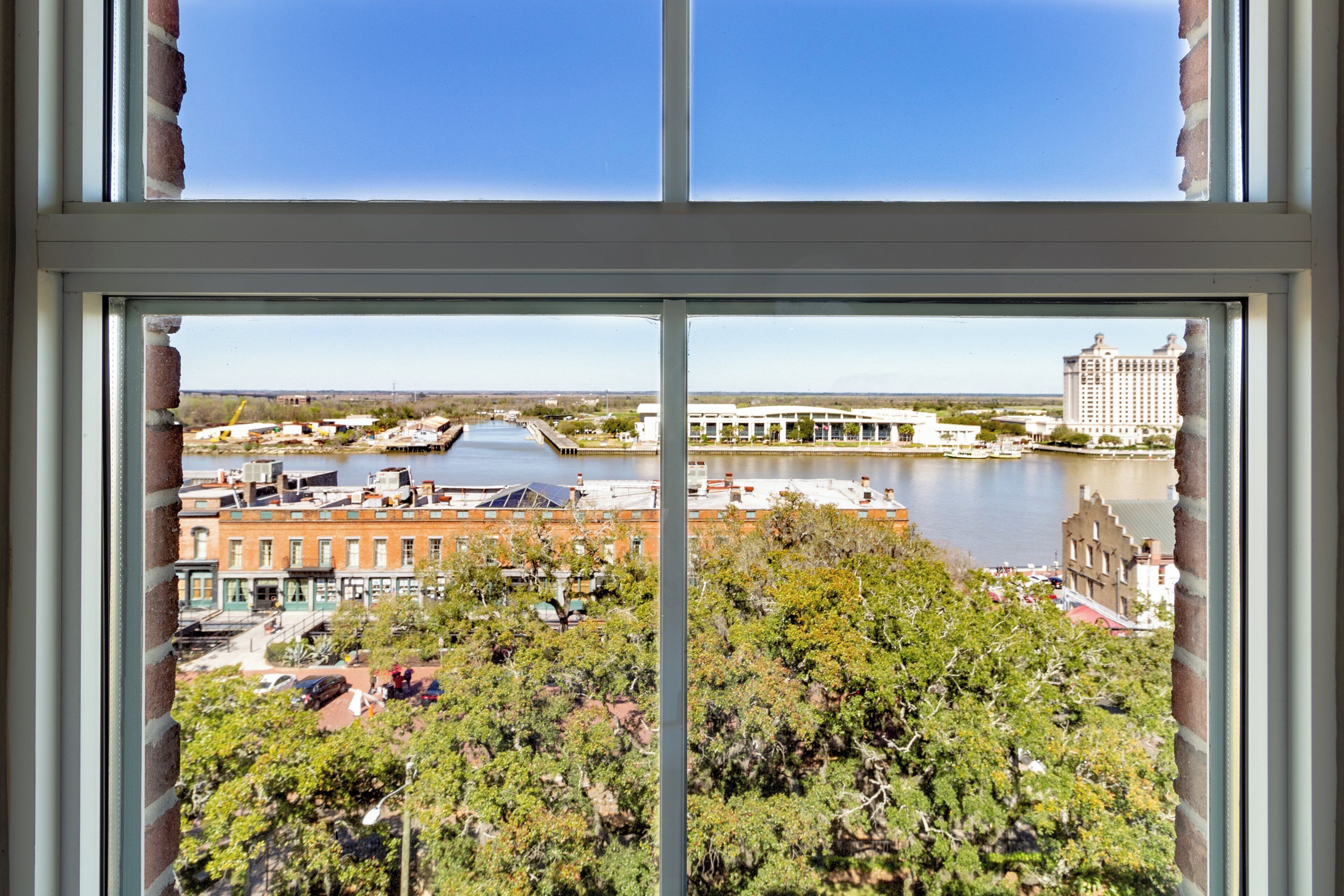 A view through a window of a riverside area with buildings, a bridge, and a large hotel.
