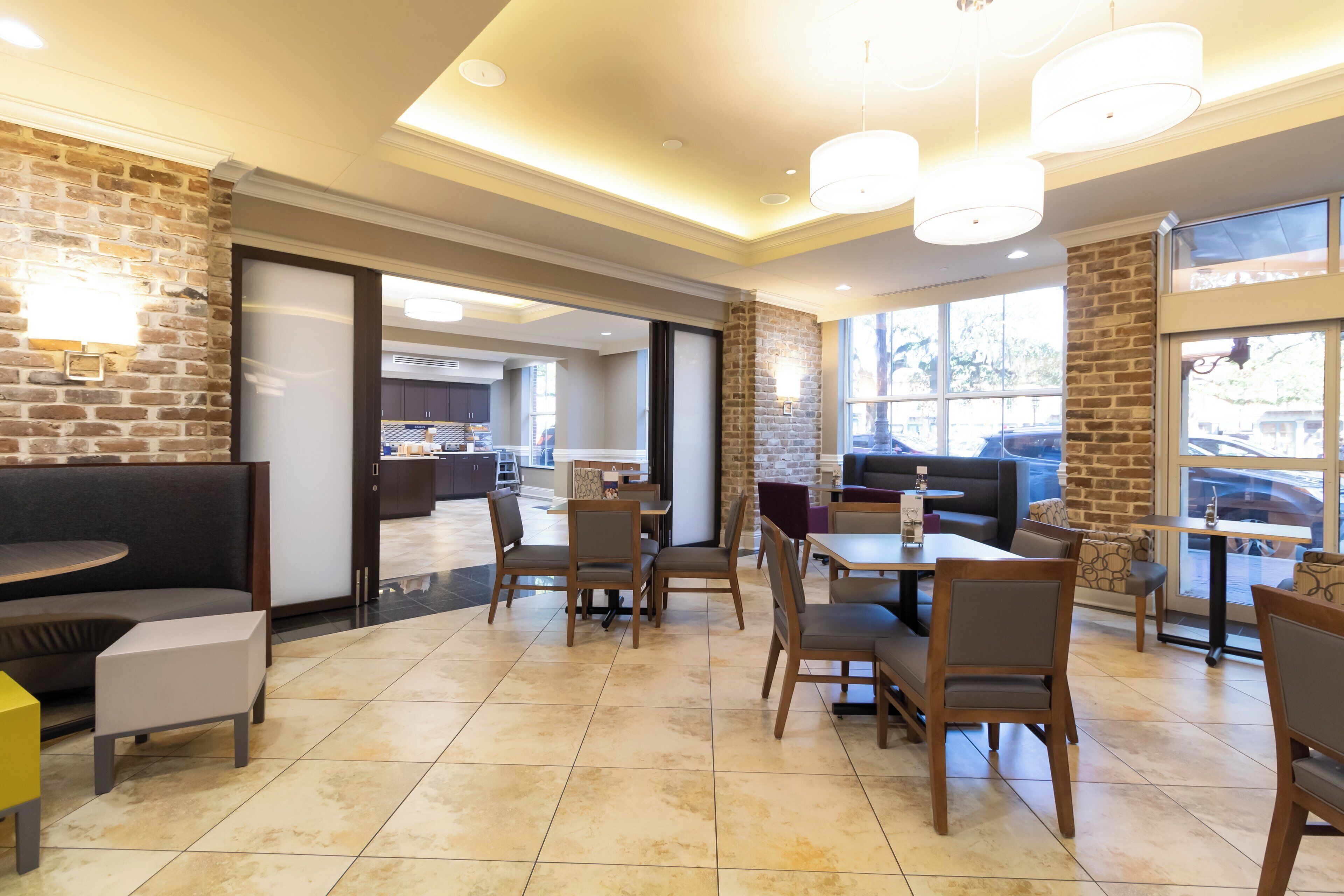 A restaurant with brick walls, wooden furniture, and large windows.
