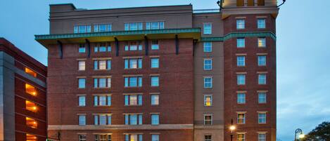 A multi-story hotel with a brick facade, multiple windows, and a green awning over the entrance.