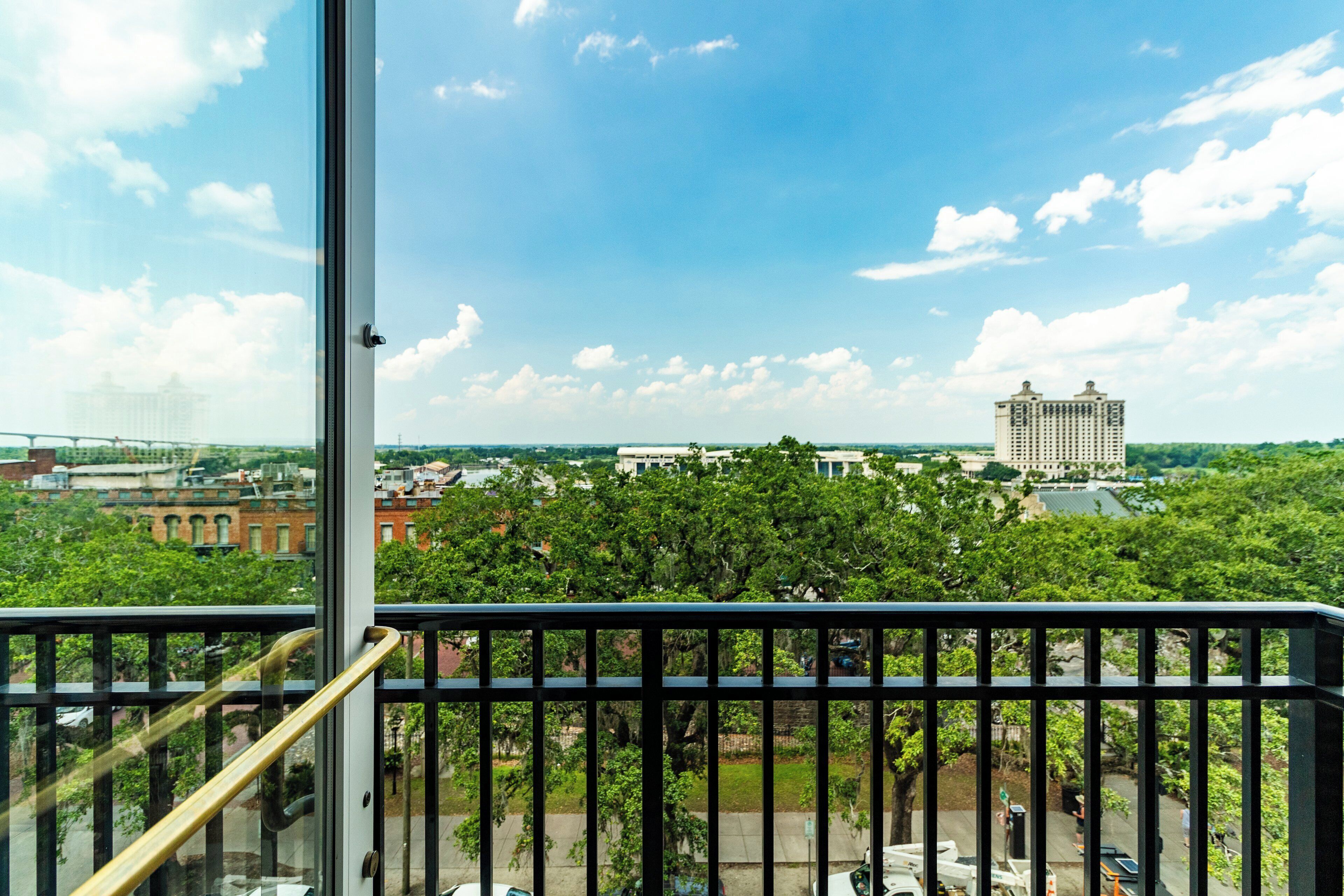 A balcony with a view of a cityscape, including buildings and greenery.