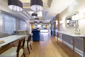 Una cocina moderna con electrodomésticos de acero inoxidable, un comedor con mesa de vidrio y una sala de estar con sofá azul.