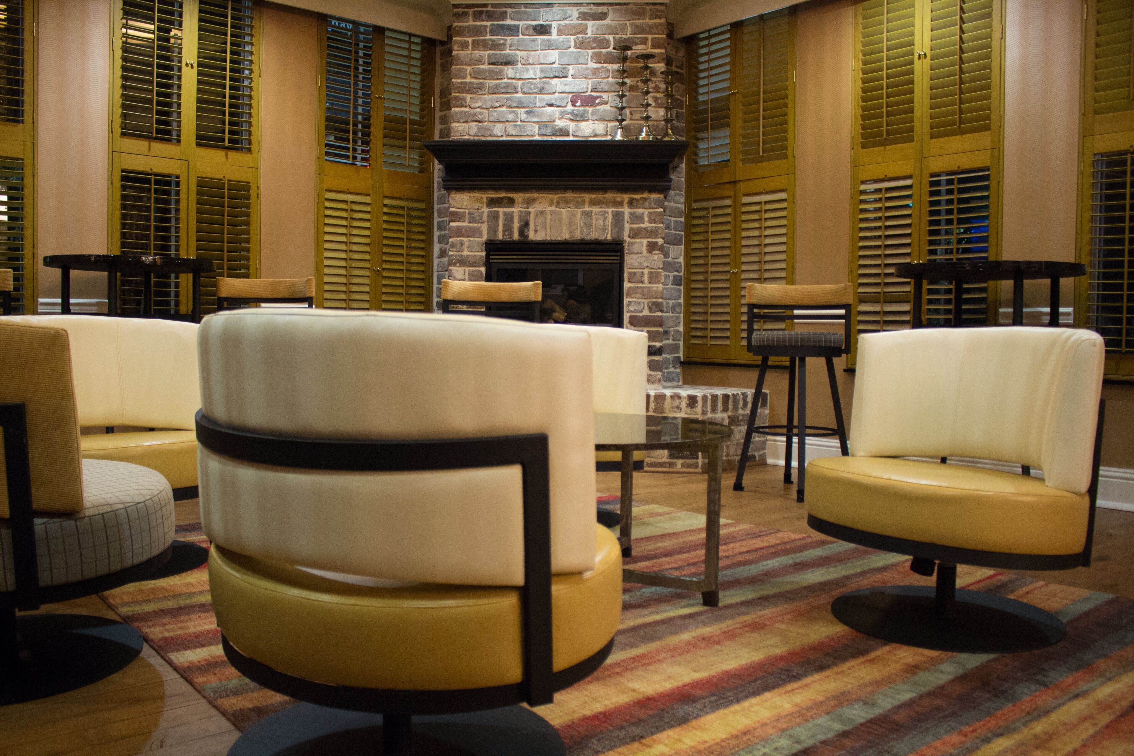 A room with a fireplace, leather armchairs, and a patterned rug.