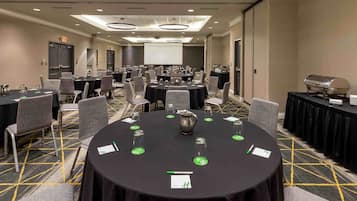 A conference room with multiple tables, chairs, and a projector screen.