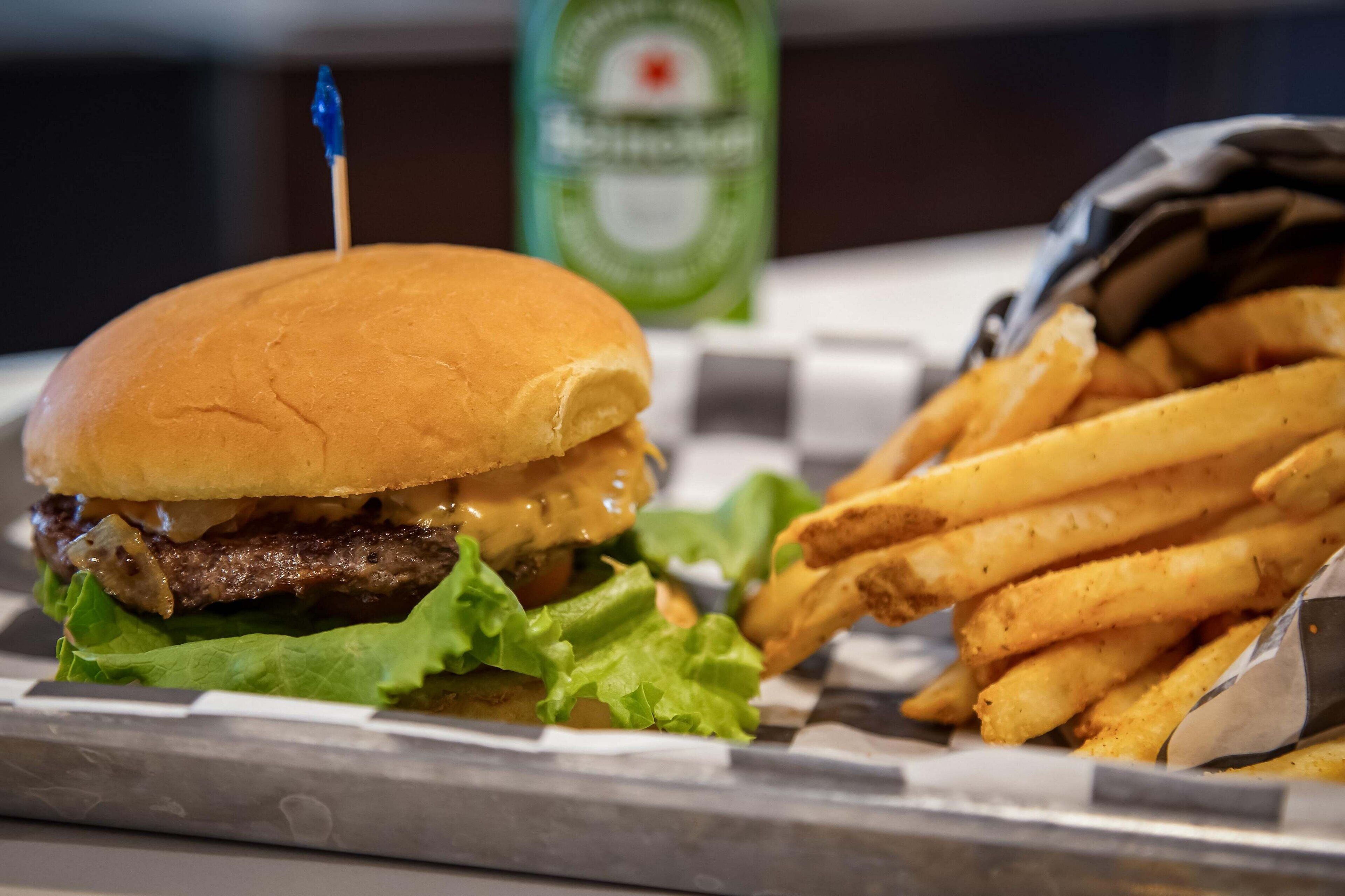 Un hamburger con uno stuzzicadenti, lattuga e formaggio, e un cestino di patatine fritte.
