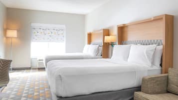 Habitación de hotel con dos camas, un escritorio, una silla y un ventanal amplio.